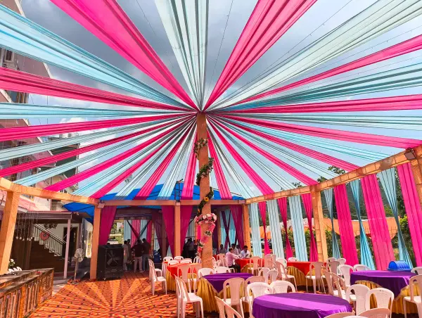Rooftop canopy with radiating pink and teal drapes over a banquet setup